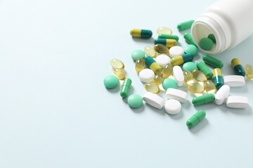 Various medicines and health pills poured from a medical white bottle, healthcare and medical top view on a colorful blue background.