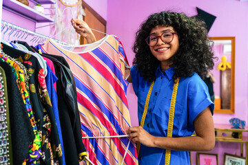 Beautiful young hispanic woman managing her home clothing e-commerce business from home - Female...