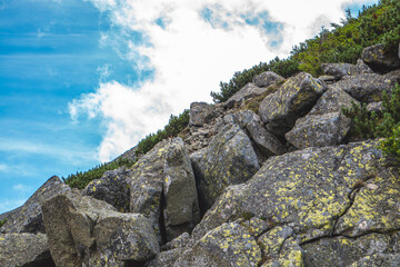 Mountain landscape on a beautiful sunny summer day, vacation in the mountains. Journey to the mountains. View of rocks and green trees in the mountains. Beautiful blue sky with white clouds.