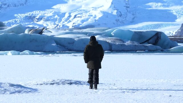 Adventurous young man walking backwards on Vatnajokull glacier in winter in Iceland