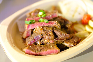Grilled steak sliced on a plate with blurred background.