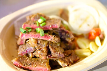 Grilled steak sliced on a plate with blurred background.