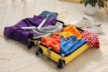 Open suitcase with traveler's belongings on floor