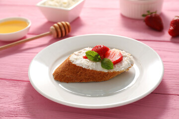 Delicious ricotta bruschetta with strawberry and mint on pink wooden table