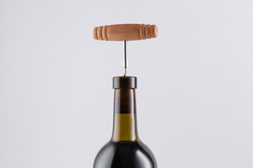 Wine bottle with corkscrew on light grey background