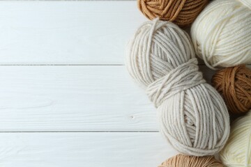 Skeins of different yarn on white wooden table, flat lay with space for text. Knitting material