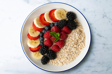 Delicious and healthy bowl of oatmeal with red fruits, raspberries, blueberries, strawberries and banana.