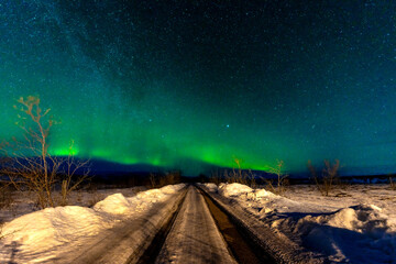 A beautiful Northern Lights in the cold Icelandic winter at night on a snowy trail. Aurora Borealis concept