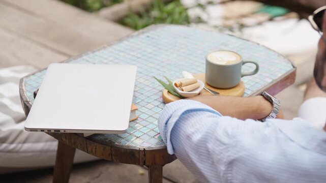 Happy Caucasian man enjoy outdoor lifestyle travel tropical island on summer beach holiday vacation. Handsome guy relaxing and drinking coffee at beach cafe and looking beautiful nature of the sea.