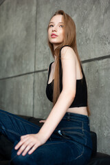 Fototapeta premium Modern female in casual clothes keeping hand in hair and smiling while sitting on the sofa