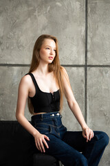 Modern female in casual clothes keeping hand in hair and smiling while sitting on the sofa