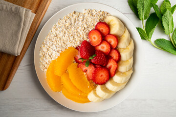 Delicious and healthy bowl of oatmeal with orange, strawberry and banana.