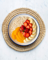 Delicious and healthy bowl of oatmeal with orange, strawberry and banana.