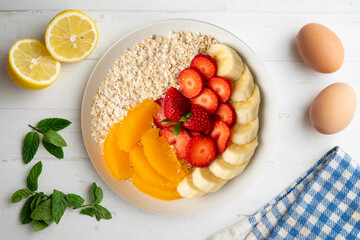 Delicious and healthy bowl of oatmeal with orange, strawberry and banana.