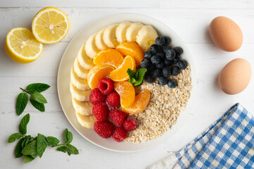 Delicious and healthy bowl of oatmeal with tangerine, banana, blueberries and raspberries.