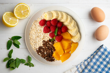 Delicious and healthy bowl of orange, chocolate, raspberries, and banana oats.