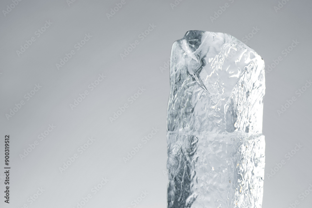 Wall mural piece of clear ice on light grey background. space for text