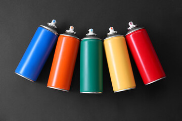 Many spray paint cans on dark gray background, top view