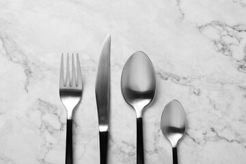 Stylish cutlery on white marble table, flat lay