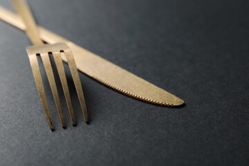 Elegant golden cutlery on black background, closeup