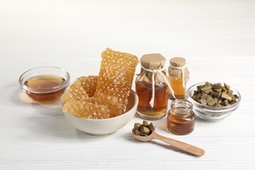 Natural honey tincture, propolis granules and sweet honeycombs on white wooden table