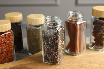 Different spices in glass jars on wooden table