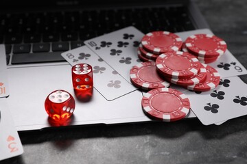 Poker chips, laptop, playing cards and dices on grey table. Online game