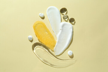 Smears of different cosmetic products on beige background, top view