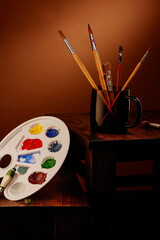 Brushes and palette for painting in gouache on wooden table
