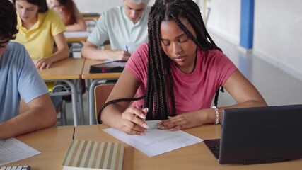 African American Girl writing essay test at college classroom - High school teenager students taking exam - Powered by Adobe