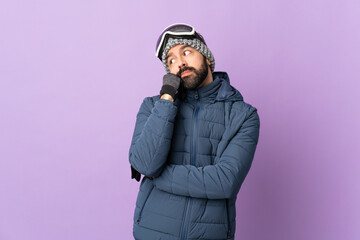 Skier man with snowboarding glasses over isolated purple background with tired and bored expression