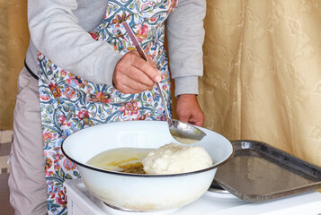 Cookery masterclass. Male hand holds ladle and pours oil over traditional flour product baursak.