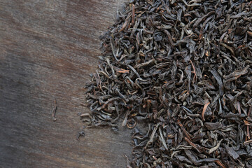 Long black tea on a dark wooden background. Top view of dried tea leaves. Tea composition