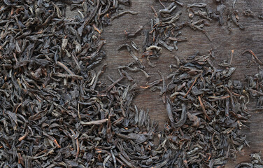 Long black tea on a dark wooden background. Top view of dried tea leaves. Tea composition