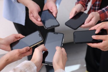 People holding smartphones with blank screens indoors, closeup