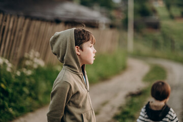 Two little boys brothers stand near the house in the mountain village in summer. Summer trip on mountain routes in Europe.
