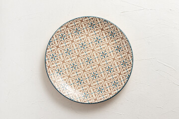 Empty porcelain plate with a pattern. On white background.