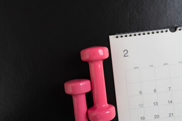 Time for exercising equipment dumbbell and calendar with black background, sport and healthy concept