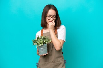 Gardener Ukrainian woman holding a plant isolated on blue background having doubts