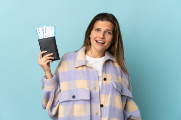 Young Slovak woman isolated on blue background happy in vacation with passport and plane tickets