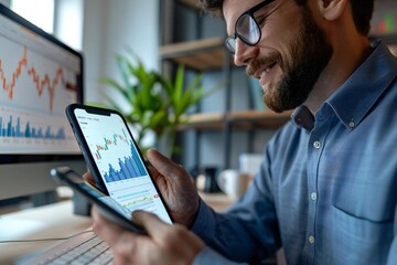 Beautiful side view of a happy, successful male stock market broker looking at rising stock charts on his phone.