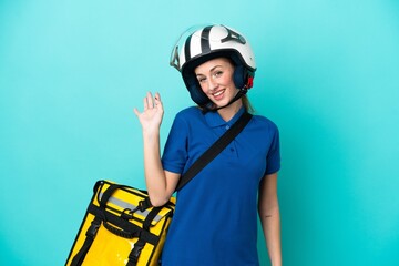 Young caucasian woman with thermal backpack isolated on white background saluting with hand with happy expression