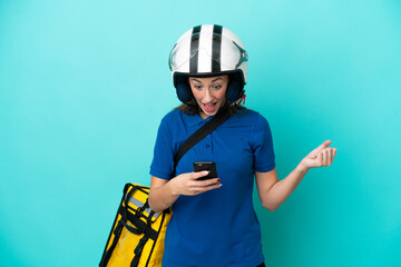 Young caucasian woman with thermal backpack isolated on white background surprised and sending a message