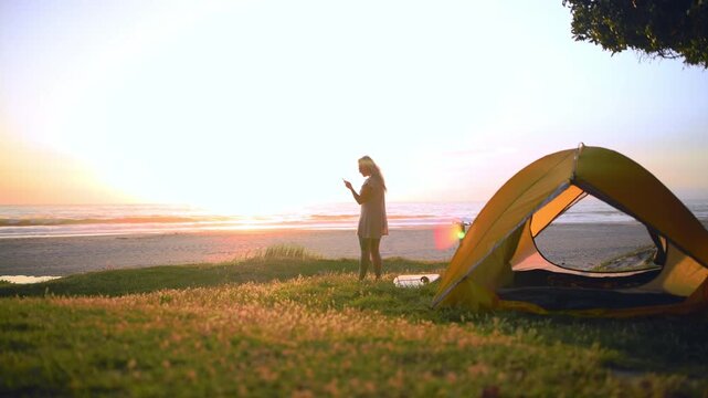 Camping, sunrise and woman in tent for picture on summer adventure, holiday and vacation outdoors. Hiking, memory and person on campsite on smartphone for social media, online post and travel blog