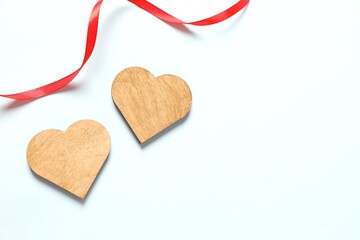 Wooden hearts with ribbon on color background, top view