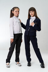A girl of European origin in a school uniform on a white background. Smiling at the camera