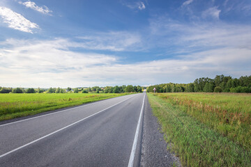 A long road with a clear blue sky and a few trees in the background