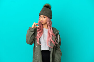 Young woman with pink hair wearing a rainproof coat isolated on blue background proud and self-satisfied