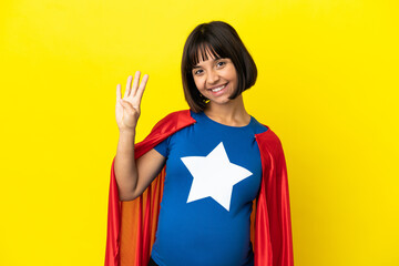 Super Hero pregnant woman isolated on yellow background happy and counting four with fingers