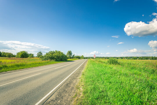 A Road With A Grassy Field On The Side